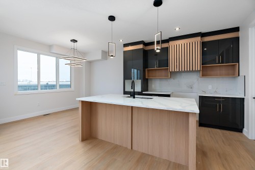 Kitchen featuring light stone counters, decorative backsplash, modern cabinets, hanging light fixtures, and an island with sink - 38 Astoria Place, Devon, AB - Indoor Photo Showing Kitchen