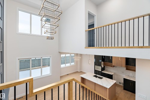 Stairs featuring a high ceiling, wood finished floors, and a chandelier - 38 Astoria Place, Devon, AB - Indoor Photo Showing Other Room
