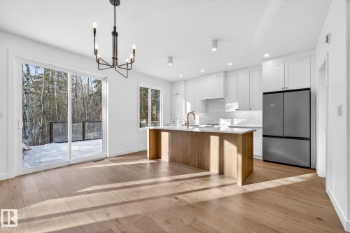 Kitchen featuring white cabinets, freestanding refrigerator, a kitchen island with sink, light wood-style flooring, and recessed lighting - 132 Heron Point Close, Rural Wetaskiwin County, AB - Indoor Photo Showing Kitchen