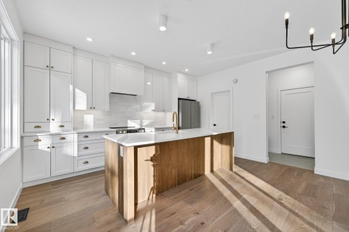 Kitchen featuring white cabinetry, a center island with sink, appliances with stainless steel finishes, backsplash, and brown cabinetry - 132 Heron Point Close, Rural Wetaskiwin County, AB - Indoor Photo Showing Kitchen With Upgraded Kitchen