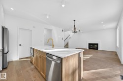 Kitchen featuring recessed lighting, a glass covered fireplace, stainless steel appliances, light wood-type flooring, and open floor plan - 