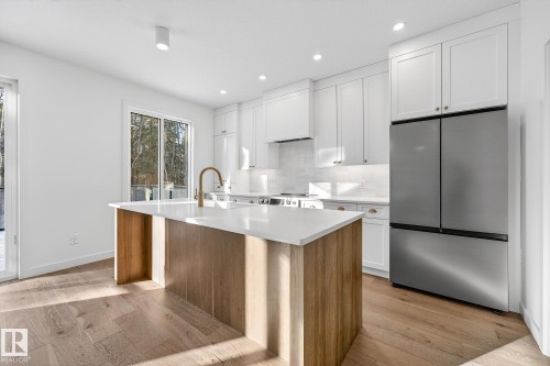 Kitchen featuring white cabinetry, freestanding refrigerator, light wood-type flooring, a center island with sink, and recessed lighting - 132 Heron Point Close, Rural Wetaskiwin County, AB - Indoor Photo Showing Kitchen With Upgraded Kitchen