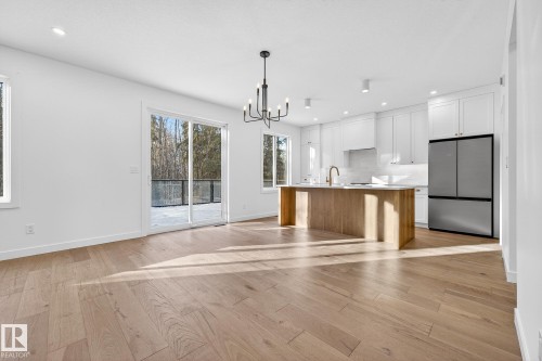 Kitchen featuring freestanding refrigerator, open floor plan, a kitchen island with sink, white cabinets, and pendant lighting - 132 Heron Point Close, Rural Wetaskiwin County, AB - Indoor Photo Showing Kitchen