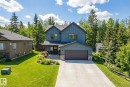 Craftsman inspired home with stone siding, a garage, concrete driveway, a front yard, and board and batten siding - 132 Heron Point Close, Rural Wetaskiwin County, AB  - Outdoor With Facade 