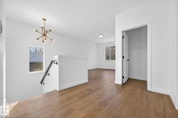 Empty room with wood finished floors and a chandelier - 