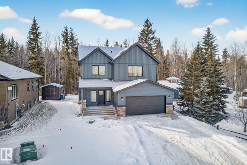 View of front of property featuring a garage, stone siding, board and batten siding, and an outdoor structure - 132 Heron Point Close, Rural Wetaskiwin County, AB - Outdoor With Facade