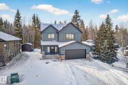 View of front of property featuring a garage, stone siding, board and batten siding, and an outdoor structure - 