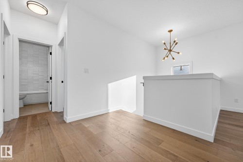 Hall with an upstairs landing, hardwood / wood-style floors, and a chandelier - 132 Heron Point Close, Rural Wetaskiwin County, AB - Indoor Photo Showing Other Room