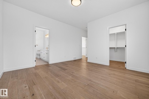Unfurnished bedroom with a spacious closet, light wood-type flooring, and connected bathroom - 132 Heron Point Close, Rural Wetaskiwin County, AB - Indoor Photo Showing Other Room