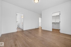 Unfurnished bedroom with a spacious closet, light wood-type flooring, and connected bathroom - 