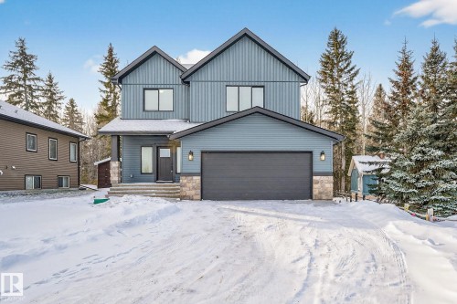 View of front of property with stone siding, a garage, and board and batten siding - 132 Heron Point Close, Rural Wetaskiwin County, AB - Outdoor With Facade