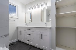 Full bath featuring double vanity, a shower, and dark tile patterned floors - 