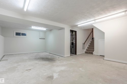 Finished basement with stairway, a textured ceiling, and heating unit - 47 Manor Drive, Sherwood Park, AB - Indoor Photo Showing Basement