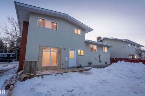 Snow covered property featuring stucco siding, a patio, and a chimney - 47 Manor Drive, Sherwood Park, AB - Outdoor With Exterior