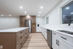 Kitchen with recessed lighting, appliances with stainless steel finishes, light stone counters, light wood-style floors, and brown cabinetry - 