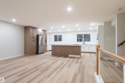 Kitchen with light wood finished floors, a center island, freestanding refrigerator, recessed lighting, and open floor plan - 