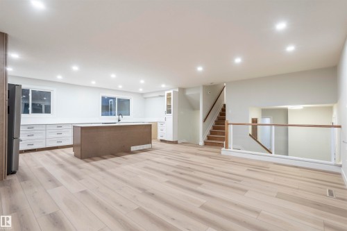 Kitchen featuring white cabinets, glass insert cabinets, light wood-type flooring, a kitchen island, and freestanding refrigerator - 47 Manor Drive, Sherwood Park, AB - Indoor