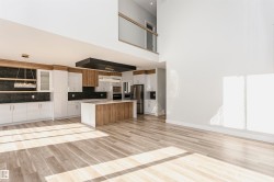 Kitchen with open floor plan, light wood-style floors, white cabinets, stainless steel fridge with ice dispenser, and a kitchen island - 