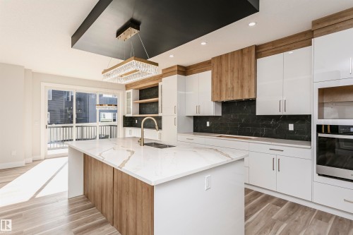 Kitchen featuring white cabinets, stainless steel built-in oven and microwave, light stone countertops, and hanging light fixtures. - 1723 19 Street, Edmonton, AB - Indoor Photo Showing Kitchen With Double Sink With Upgraded Kitchen