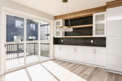 Bar with white cabinetry, pendant lighting, light wood-type flooring, glass insert cabinets, and decorative backsplash - 
