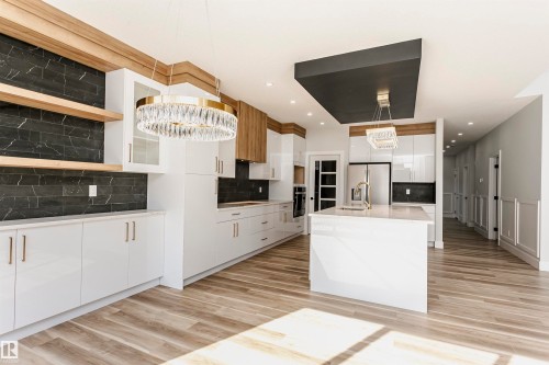Kitchen featuring white cabinetry, decorative light fixtures, tasteful backsplash, a kitchen island with sink, and light wood-style floors - 1723 19 Street, Edmonton, AB - Indoor Photo Showing Kitchen