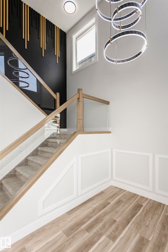 Staircase featuring LVP finished floors, a chandelier, and a decorative wall - 1723 19 Street, Edmonton, AB - Indoor Photo Showing Other Room