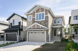 View of front facade with stone siding, driveway, and an attached garage - 