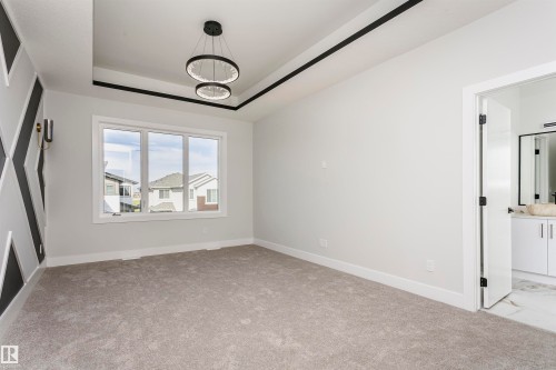 Unfurnished bedroom featuring a tray ceiling, light carpet, and connected bathroom - 1723 19 Street, Edmonton, AB - Indoor Photo Showing Other Room