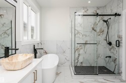 Full bath featuring marble finish floors, vanity, a freestanding tub, a marble finish shower, and tile walls - 