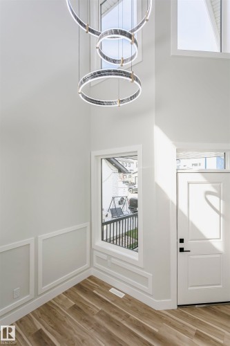 Foyer entrance featuring light wood-style floors, a chandelier, a decorative wall, and a high ceiling - 1723 19 Street, Edmonton, AB - Indoor Photo Showing Other Room