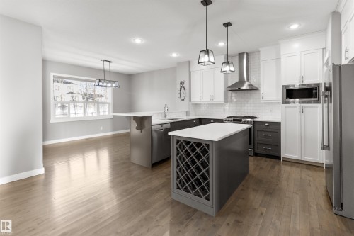 Kitchen with hanging light fixtures, a peninsula, a breakfast bar area, wall chimney exhaust hood, and recessed lighting - 107 Cresthaven Grove, Ardrossan, AB - Indoor Photo Showing Kitchen With Upgraded Kitchen