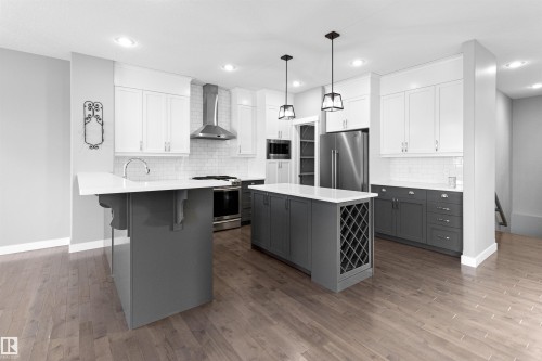 Kitchen featuring gray cabinetry, a kitchen bar, a kitchen island, appliances with stainless steel finishes, and wall chimney exhaust hood - 107 Cresthaven Grove, Ardrossan, AB - Indoor Photo Showing Kitchen With Stainless Steel Kitchen With Upgraded Kitchen
