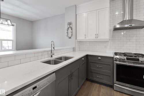 Kitchen featuring stainless steel appliances, ventilation hood, gray cabinets, and light stone counters - 107 Cresthaven Grove, Ardrossan, AB - Indoor Photo Showing Kitchen With Double Sink