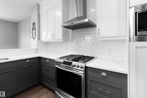 Kitchen featuring stainless steel appliances, wall chimney range hood, white cabinets, dark wood-type flooring, and tasteful backsplash - 107 Cresthaven Grove, Ardrossan, AB - Indoor Photo Showing Kitchen With Upgraded Kitchen
