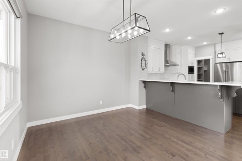 Kitchen featuring a kitchen bar, white cabinets, a peninsula, high end refrigerator, and recessed lighting - 107 Cresthaven Grove, Ardrossan, AB - Indoor Photo Showing Kitchen