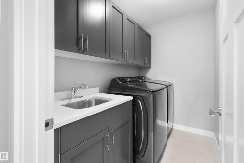Washroom featuring cabinet space, washing machine and dryer, light tile patterned floors, and a textured ceiling - 107 Cresthaven Grove, Ardrossan, AB - Indoor Photo Showing Laundry Room