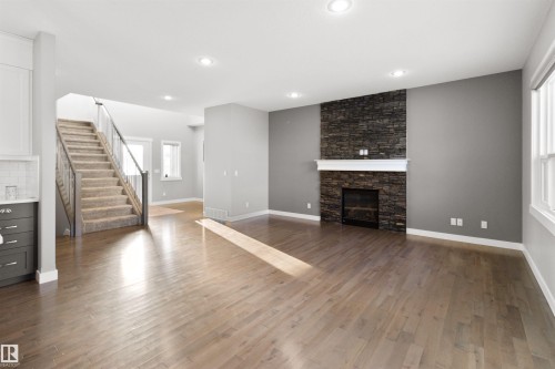 Unfurnished living room with stairway, a fireplace, dark wood-style flooring, plenty of natural light, and recessed lighting - 107 Cresthaven Grove, Ardrossan, AB - Indoor Photo Showing Other Room With Fireplace