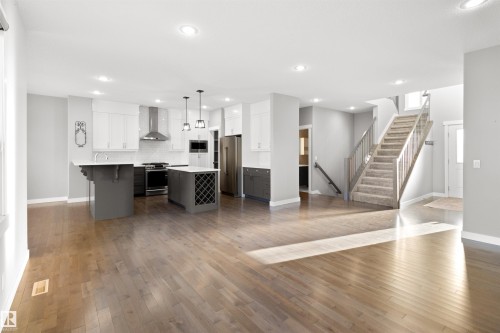 Kitchen with a kitchen breakfast bar, open floor plan, decorative light fixtures, stainless steel appliances, and wall chimney exhaust hood - 107 Cresthaven Grove, Ardrossan, AB - Indoor Photo Showing Kitchen With Upgraded Kitchen