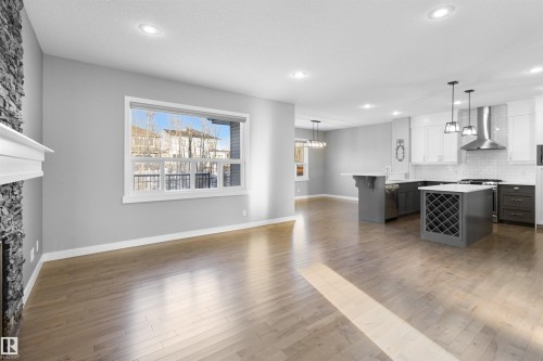 Kitchen featuring a kitchen bar, decorative light fixtures, wall chimney range hood, white cabinetry, and gray cabinetry - 107 Cresthaven Grove, Ardrossan, AB - Indoor Photo Showing Kitchen With Upgraded Kitchen