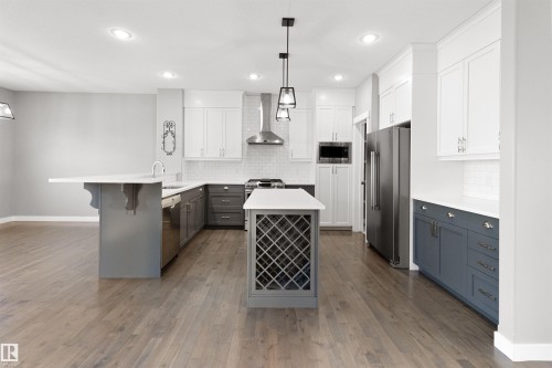 Kitchen with gray cabinetry, a peninsula, a kitchen bar, pendant lighting, and stainless steel appliances - 107 Cresthaven Grove, Ardrossan, AB - Indoor Photo Showing Kitchen With Upgraded Kitchen