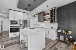 Kitchen with white cabinets, open shelves, stainless steel appliances, a center island with sink, and a kitchen breakfast bar - 