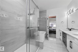 Full bathroom featuring ensuite bath, double vanity, a freestanding bath, and a marble finish shower - 