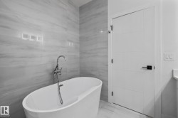Bathroom with vanity, a soaking tub, and tile walls - 