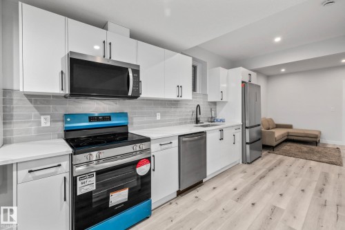 Kitchen featuring appliances with stainless steel finishes, tasteful backsplash, light wood-style flooring, white cabinetry, and recessed lighting - 5304 Kimball Place, Edmonton, AB - Indoor Photo Showing Kitchen