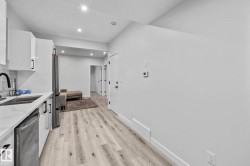 Kitchen featuring white cabinets, appliances with stainless steel finishes, light wood-style flooring, recessed lighting, and light stone counters - 