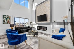 Living room featuring a high ceiling, wood finished floors, healthy amount of natural light, and a glass covered fireplace - 