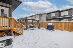 Yard layered in snow featuring a fenced backyard, a gazebo, a residential view, a deck, and a patio - 