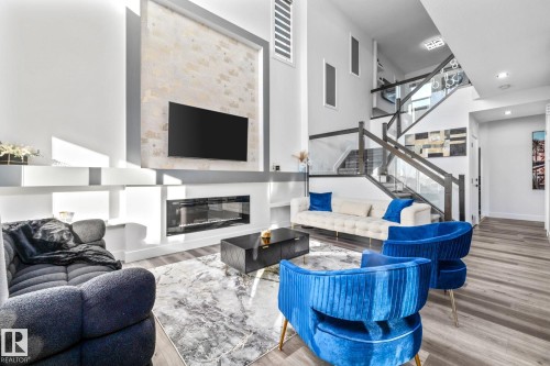 Living room with wood finished floors, a glass covered fireplace, stairway, and recessed lighting - 5304 Kimball Place, Edmonton, AB - Indoor Photo Showing Living Room With Fireplace