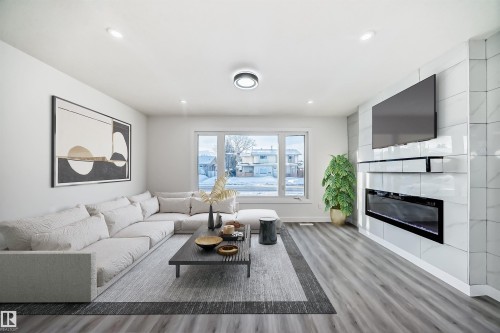 Living area featuring light wood-style flooring, recessed lighting, and a large fireplace - 14505 23 Street Nw, Edmonton, AB - Indoor Photo Showing Living Room With Fireplace