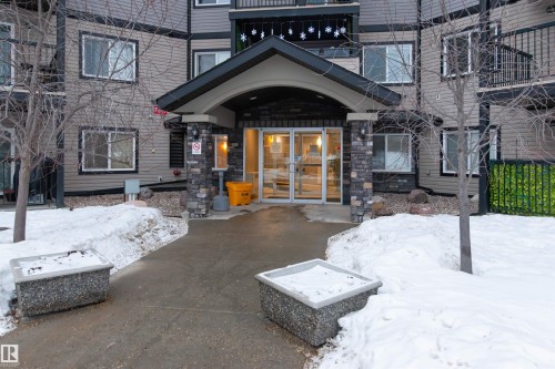 Snow covered property entrance with french doors and stone siding - 303 5951 165 Avenue, Edmonton, AB - Outdoor With Balcony